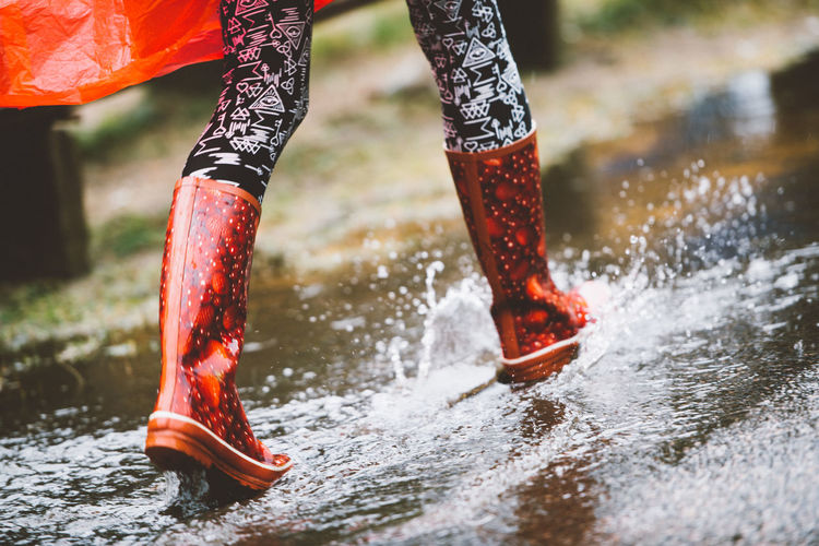 Low section of woman running on road during rainy season