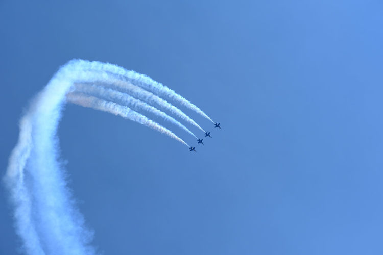 Low angle view of airshow flying against sky