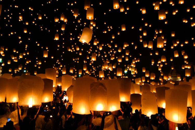 Group of people with illuminated paper lanterns at night