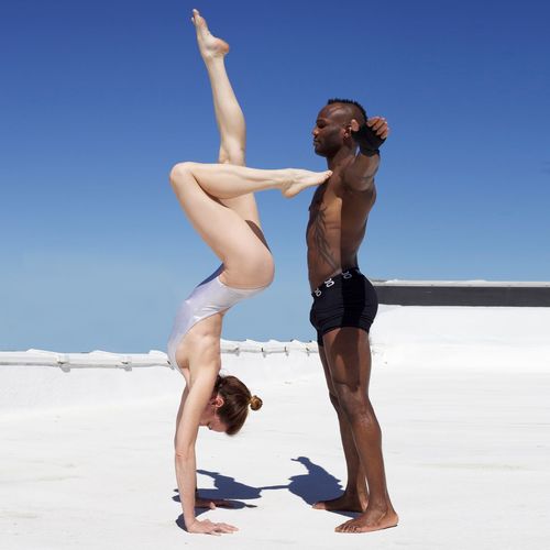 Young man supporting woman doing handstand on desert