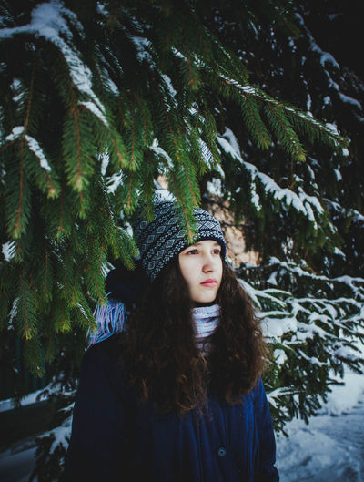 Portrait of beautiful woman standing against trees in winter