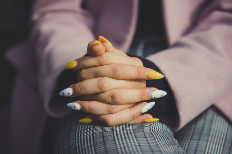 Midsection of woman sitting with hands clasped