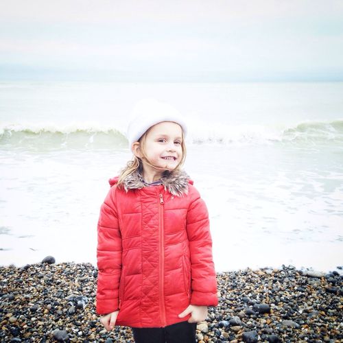 Portrait of happy girl standing at sea shore
