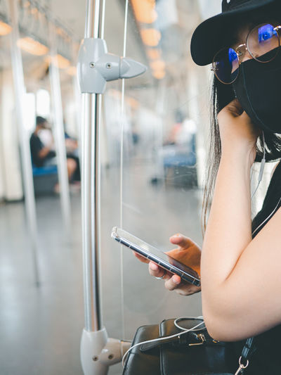 Close-up woman wear protective mask and using smartphone in public transport.