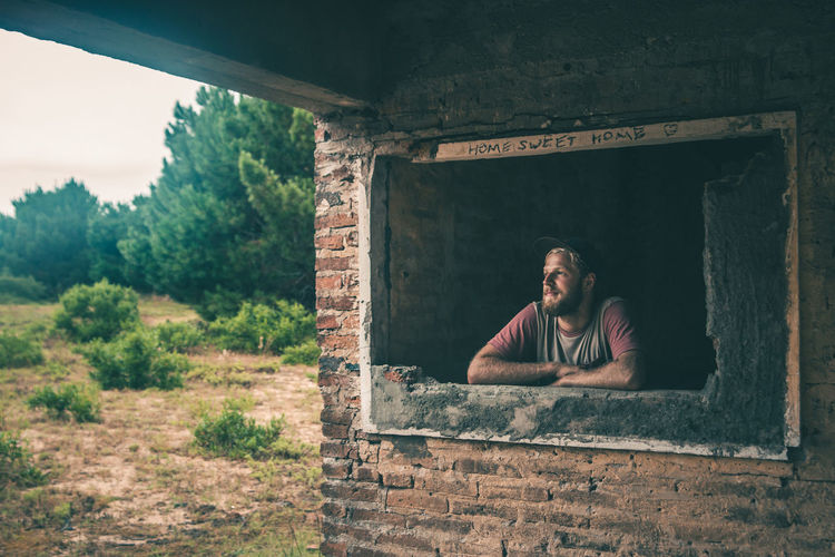 Man looking through window of incomplete house