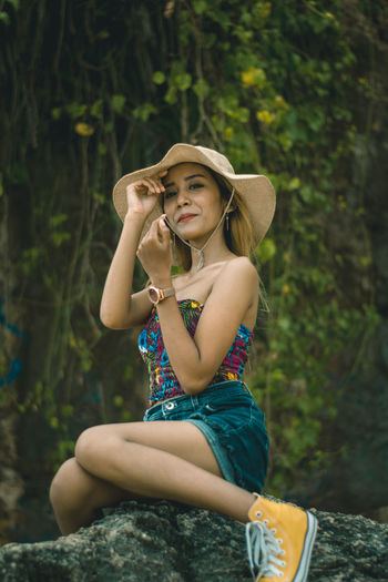 Portrait of a beautiful young woman sitting on rock