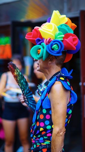 Side view of man wearing colorful costume while standing in city during parade