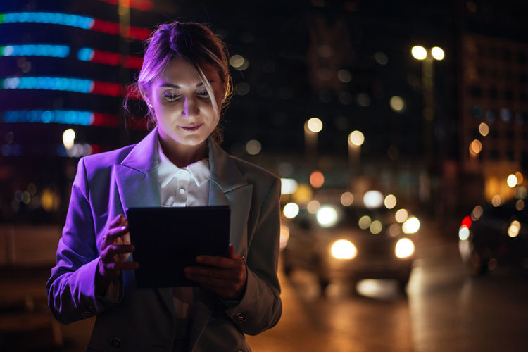 Young woman using digital tablet at night