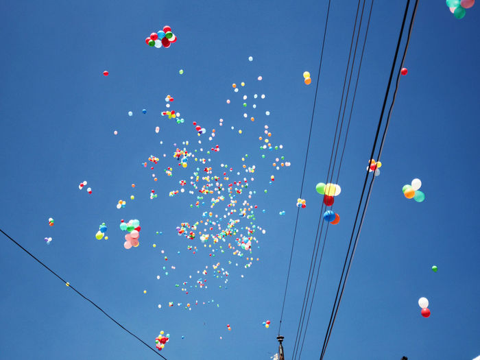 Low angle view of colorful balloons against clear blue sky