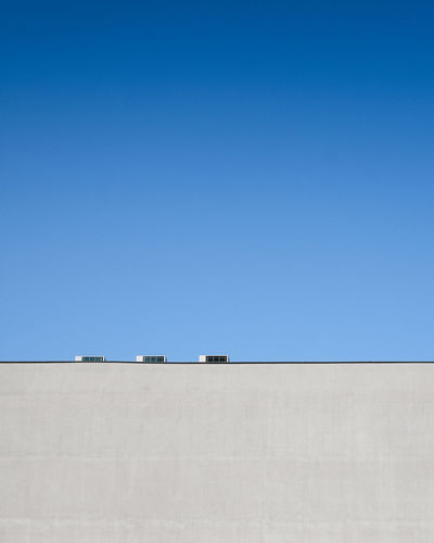 Low angle view of building part against clear blue sky