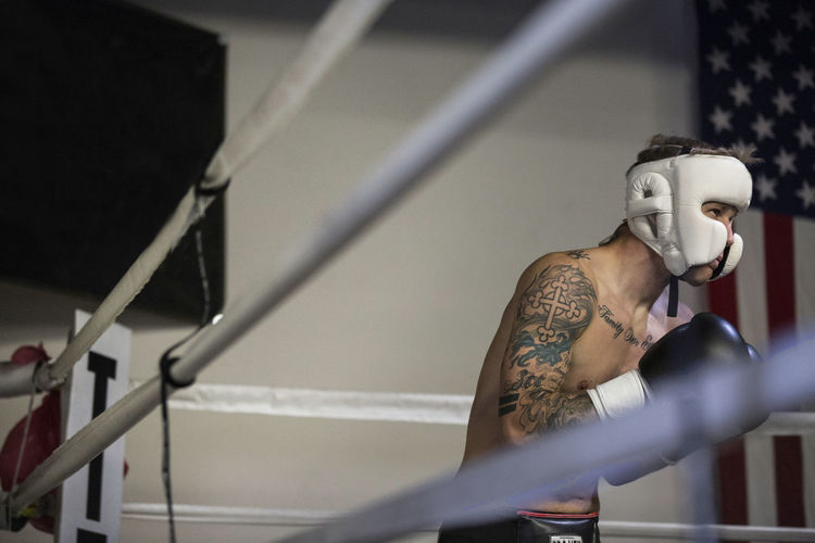 Shirtless boxer practicing in boxing ring at gym
