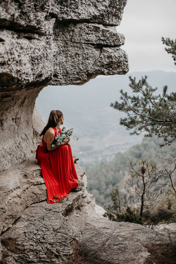 Rear view of woman walking on rock against trees