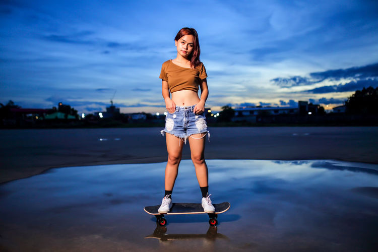 Asian women playing surf skate or skates board outdoors.