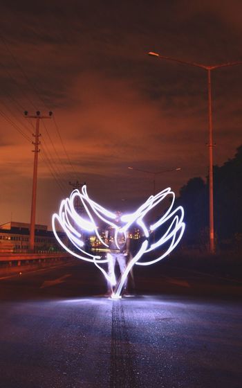 Digital composite image of illuminated light against sky at night