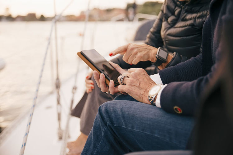 Midsection of senior women using mobile phone on yacht