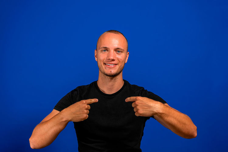 Portrait of smiling man standing against blue background