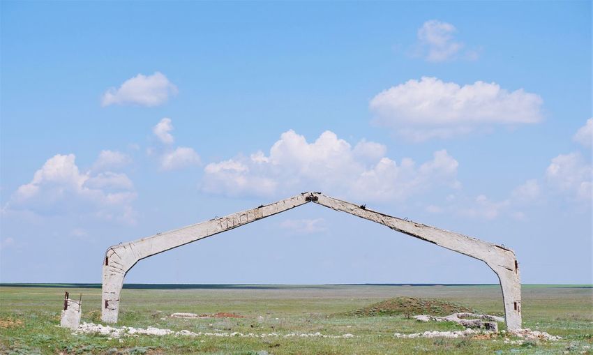 Reinforced concrete arch in a field against the sky with clouds