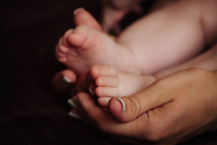 Children's feet in the hands of the mother.