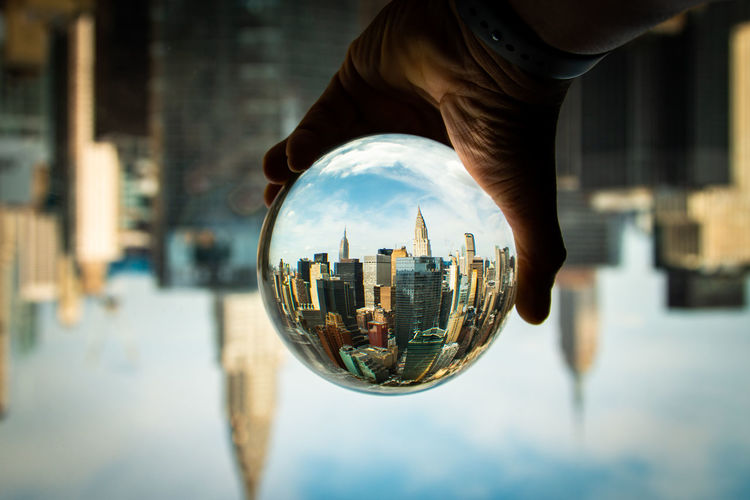 Cropped hand of person holding crystal ball in city