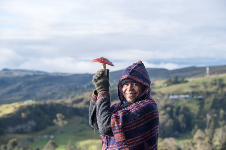 Colombian native american man in traditional clothing holding mushroom like umbrella