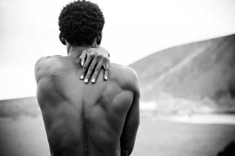 Rear view of shirtless muscular man standing at beach