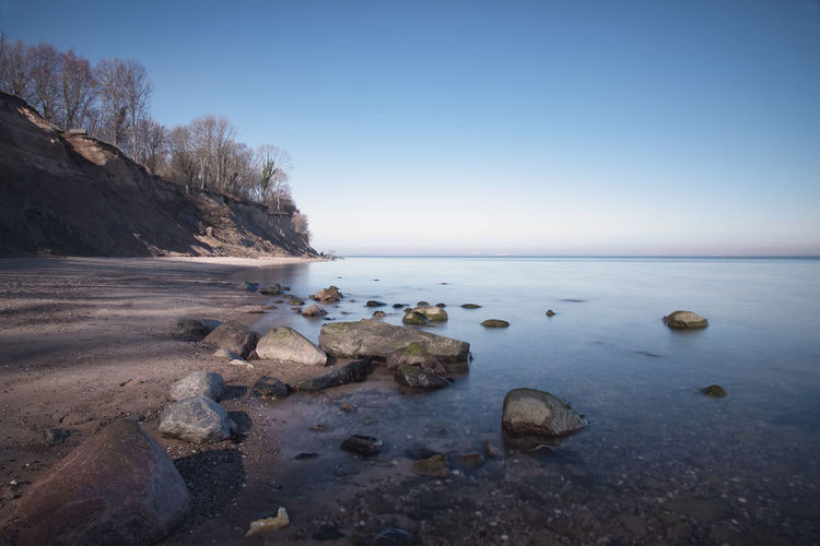 Rocks in sea against clear sky