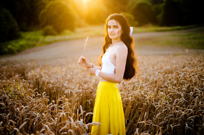 A girl runs through a field with spikelets against the background of the setting sun