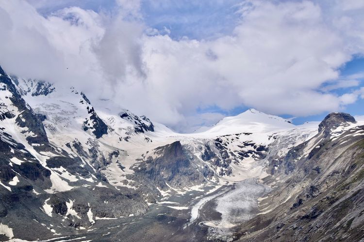 Scenic view of glacier and snowcapped mountains against sky
