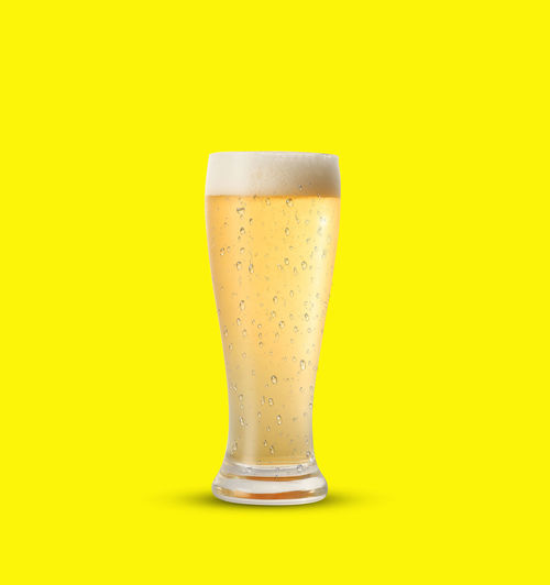 Close-up of beer glass against yellow background