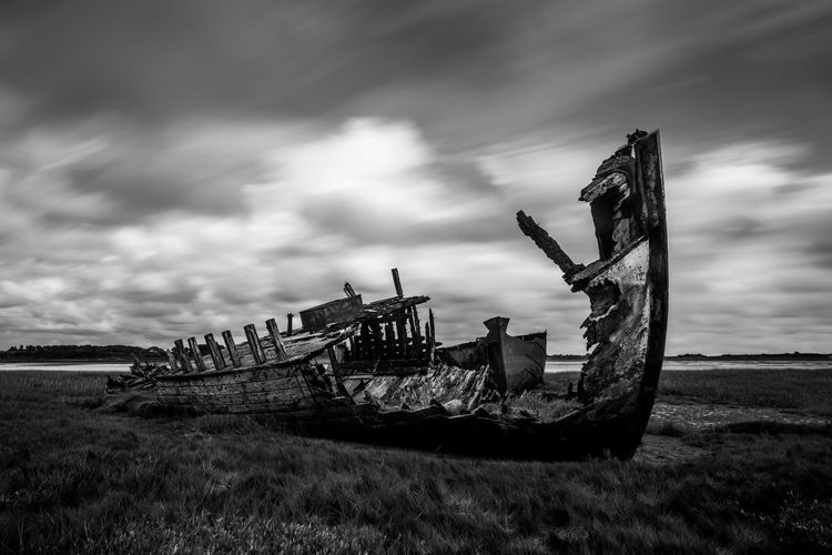 Abandoned ship on field against sky
