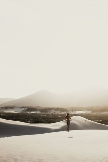 Woman running in sand dunes in sunny day