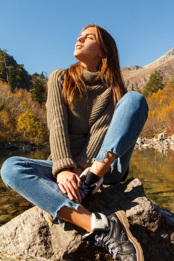 Midsection of woman sitting on mountain against sky
