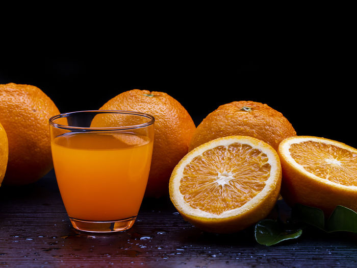 Healthy food, freshness orange fruit, and orange juice in the clear glass on the black background.