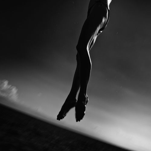 Low section of woman diving on sea against sky