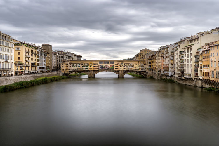 Ponte vecchio over river in city against sky