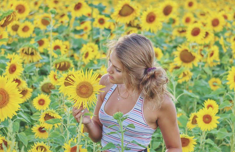Rear view of woman against yellow sunflower on field