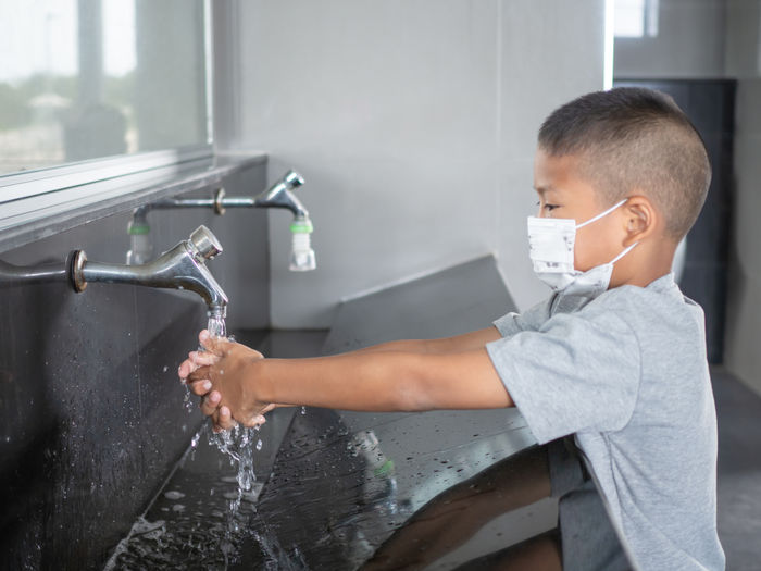 Boy washing hands from faucet in bathroom