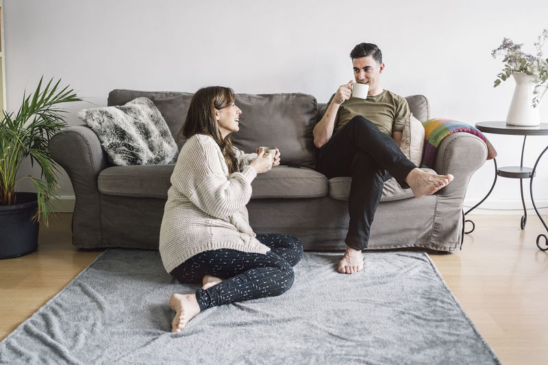 Couple talking while sitting in living room at home