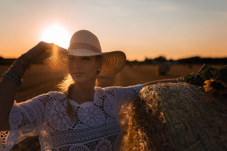 Woman wearing straw hat against sun during sunset