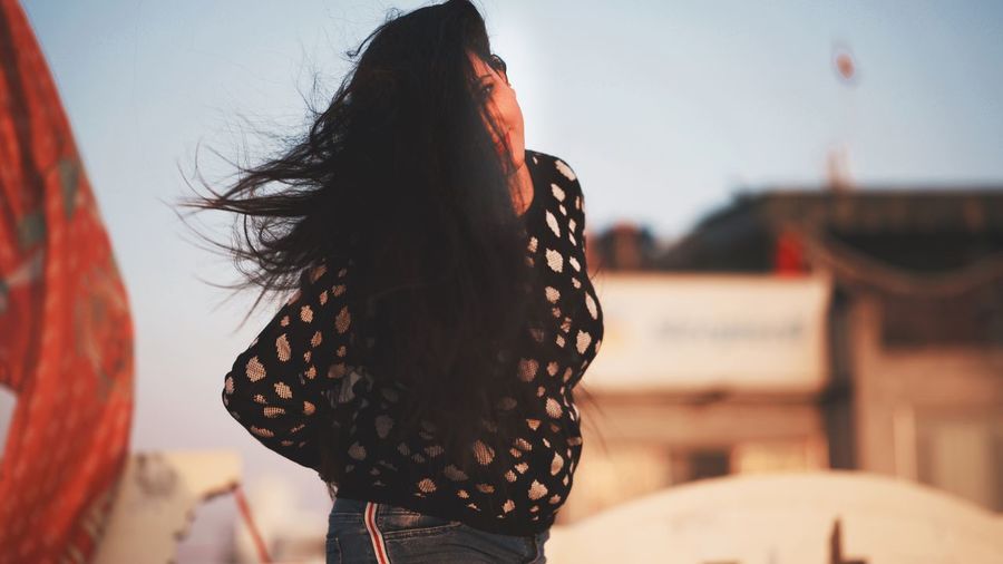 Rear view of woman standing against sky