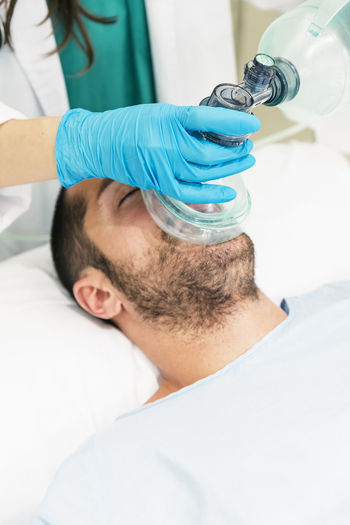 Midsection of doctor wearing oxygen mask to patient