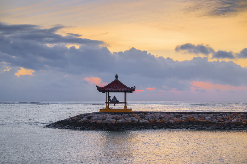 Lifeguard hut on beach against sky during sunset