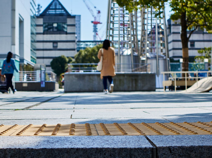 Rear view of woman walking on sidewalk