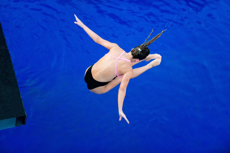 High angle view of woman with arms outstretched diving into swimming pool