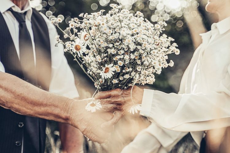 Midsection of people holding flower bouquet