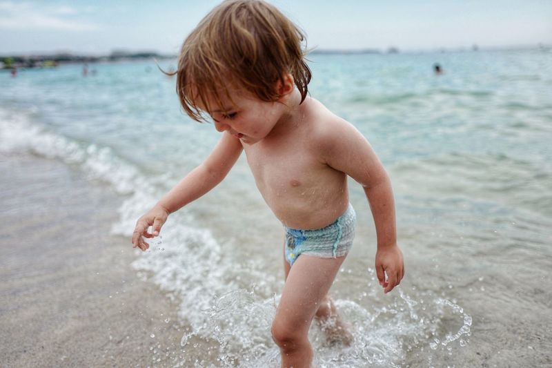 Shirtless boy wading in sea