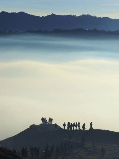 Silhouette people on mountain against sky
