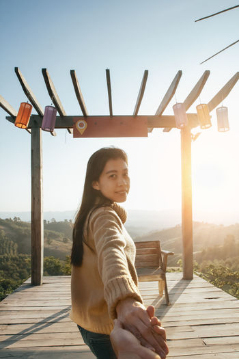 Portrait of girl standing on wood against sky