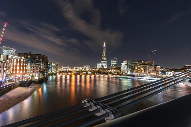 Illuminated shard london bridge by thames river against sky in city at night