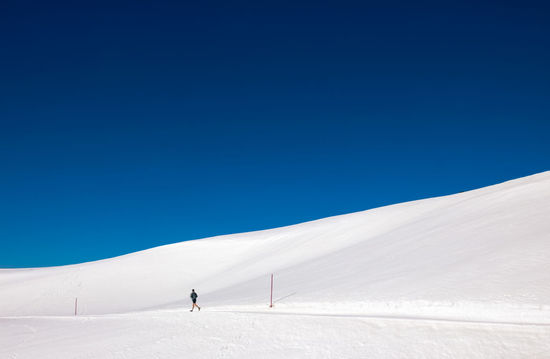 People on snowcapped mountain against clear blue sky